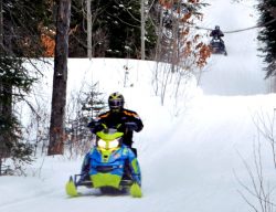 Photo of snowmobilers on a trail.